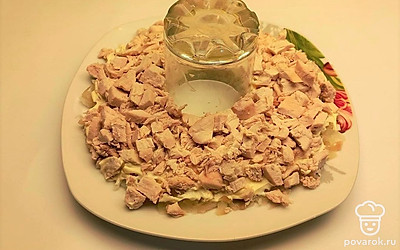 Чтобы выстроить форму браслета, в середину тарелки поместите стакан. Вокруг стакана выложите слои салата. Первым слоем выложите отварной картофель, смажьте его майонезом, затем на него выложите кусочки нарезанного куриного филе.