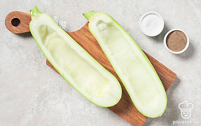 Разрежьте кабачки вдоль на две части и выскоблите мякоть, чтобы оставались достаточно толстые стенки. Посолите получившиеся лодочки-основания.