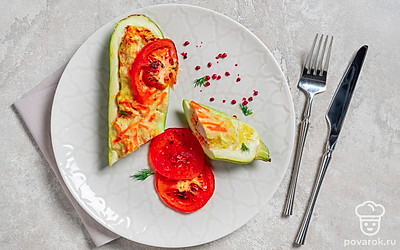 Выложите лодочки из кабачков на порционные тарелки. Положите рядом несколько запеченных кружочков помидоров. 