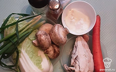 Шампиньоны промойте, почистите, сняв пленки со шляпок. Также срежьте потемневшие срезы на ножках. Хорошо обсушите грибы, иначе напитавшись влагой, они станут водянистыми. Нарежьте шампиньоны дольками. Пекинскую капусту помойте и тонко нашинкуйте, убрав толстые белые листья. Отварное куриное филе нарежьте мелкими кубиками. Морковь почистите и натрите на крупной терке. Зелёный лук мелко порубите. Чеснок пропустите через пресс.