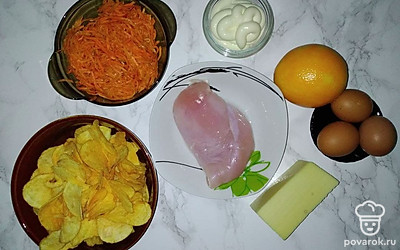 Отварите и очистите яйца. Натрите их на крупной терке. Посолите воду и отварите в ней курино филе. Остудите филе и нарежьте кусочками. Натрите сыр на крупной терке. Очистите и нарежьте апельсин маленькими кусочками. Часть целых чипсов отложите, остальные мелко накрошите.