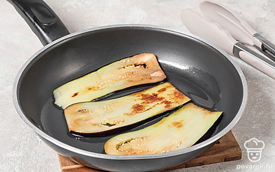 Нарежьте баклажаны вдоль на пластинки толщиной около 0,5 см. Посолите и оставьте на 5 минут. Потом обжарьте на разогретом растительном масле по 2 минуты с каждой стороны на среднем огне. Переложите баклажаны на бумажные полотенца.