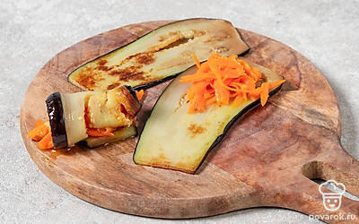 Положите на край каждого ломтика баклажана 1 ст.л. моркови и сверните рулетиком.