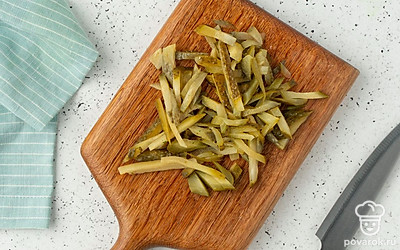 Нарежьте соленые огурцы тонкой соломкой.