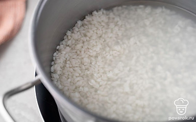 Всыпьте в кастрюлю рис. Залейте его водой и поставьте на средний огонь. Варите крупу до полуготовности в течение 10 минут после того, как вода закипит.
