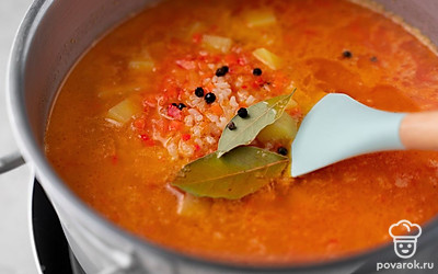 Добавьте в кастрюлю овощную зажарку, горошины перца и лавровый лист. Перемешайте.