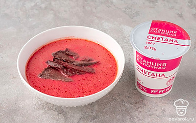 Нарежьте мясо на небольшие кусочки. Положите в тарелку немного борща. Добавьте ложку сметаны, перемешайте. Сверху выложите кусочки говядины.