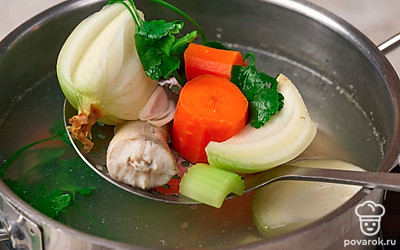 Когда бульон закипит, убавьте нагрев до минимума. Положите в него репчатый лук, одну морковь, корень сельдерея и петрушку. 