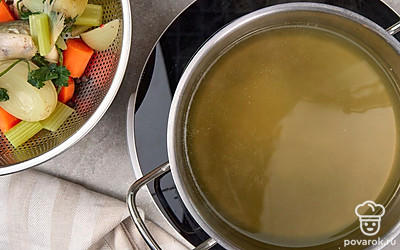 Достаньте из кастрюли овощи, зелень и части рыбы. Сам бульон процедите через сито, а затем снова доведите до кипения на среднем огне.