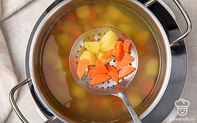 Оставшуюся морковь нарежьте полукруглыми дольками. Добавьте ее в кастрюлю с картофелем.