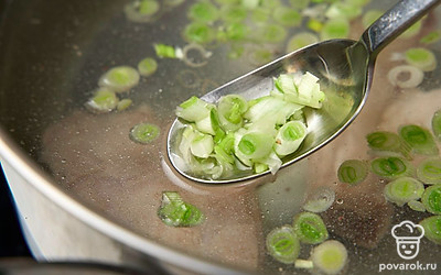 Снова положите ребрышки в кастрюлю, добавьте к ним белую часть зеленого лука. Поставьте кастрюлю на сильный огонь. Дождитесь кипения и убавьте огонь до среднего. 