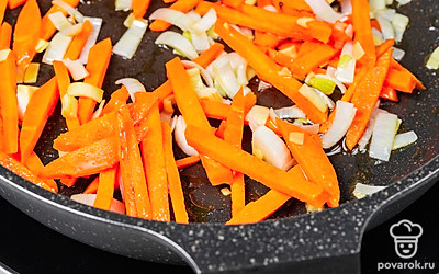 Поставьте сковороду на сильный огонь, разогрейте в ней масло. Опустите в масло лук, обжарьте его до золотистого оттенка. Убавьте огонь, положите к луку морковь и обжаривайте все вместе 2-3 минуты.