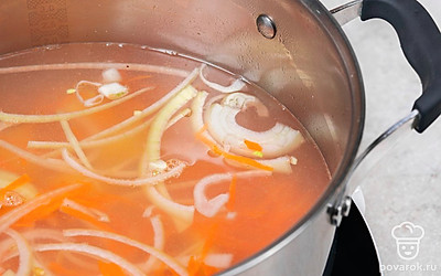 Всыпьте в бульон перловую крупу, поварите 3-4 минуты. Добавьте картофель, морковь и лук.