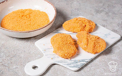 В отдельную миску выложите оставшуюся панировочную смесь. Из готового фарша сформируйте небольшие наггетсы и обваляйте их в сухарях со всех сторон.