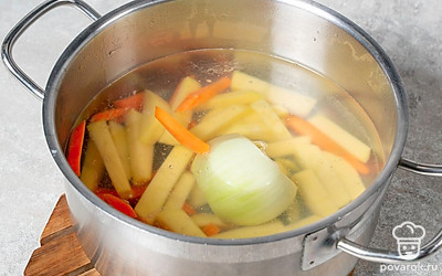 Половинку луковицы добавьте в кастрюлю с картофелем и морковью. Продолжайте варить.