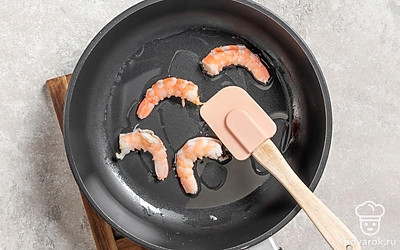 Добавьте в сковороду с чесночным маслом очищенные креветки.