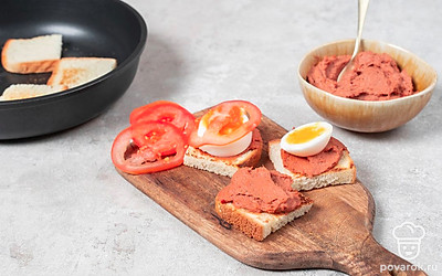 Намажьте массу на обжаренный хлеб. Разрежьте яйца на толстые кружочки, так же измельчите помидоры. Выложите на канапе яйца, а сверху уложите нарезанные томаты и украсьте зеленью.