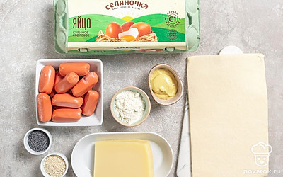 Куриное яйцо помойте. Тесто разморозьте. Сосиски очистите от пленки. Разогрейте духовку до 180 градусов. Застелите противень пергаментом или силиконовым ковриком.