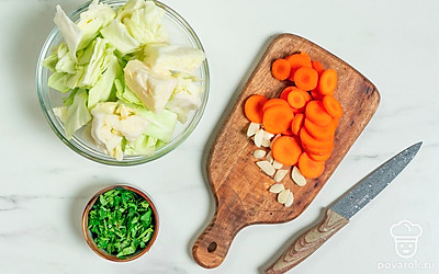 Капусту крупно нарежьте вместе с кочерыжкой. Чеснок нарежьте пластинками, а морковь — кружочками. Зелень измельчите. 