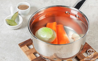 Подготовьте овощной бульон. Разрежьте одну морковь на две части. Выложите в кастрюлю с водой. Добавьте одну луковицу и чеснок. Доведите до кипения. Варите 15 минут. Затем опустите лавровый лист и перец. Варите еще 5 минут. 