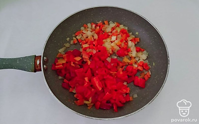 Репчатый лук и морковь нарежьте мелкими кубиками. В большой сковороде разогрейте оливковое масло и выложите нарезанный лук с морковью. Обжарьте овощи 3-5 минут. Затем, нарежьте мелкими кубиками болгарский перец и добавьте в сковороду. Обжарьте 3-5 минут на умеренном огне.