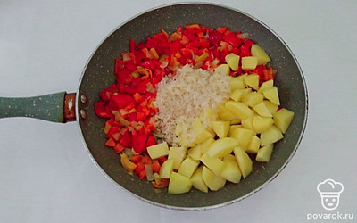Очищенный картофель нарежьте небольшими кусочками произвольной формы, промойте под проточной водой, чтобы ушел лишний крахмал, и выложите в сковороду к обжаренным овощам. Также, в сковороду выложите промытый рис. Перемешайте овощи с рисом и залейте водой. Варите суп под закрытой крышкой на умеренном огне 15 минут.
