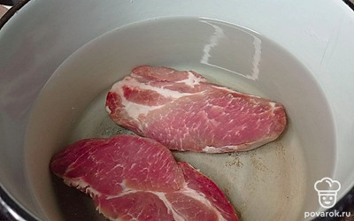 Подготовленное мясо переложите в большую кастрюлю с кипящей водой, время от времени аккуратно снимайте специальной шумовкой всю лишнюю накипь. Посолите и поперчите бульон и варите около 60 минут до мягкости свинины.