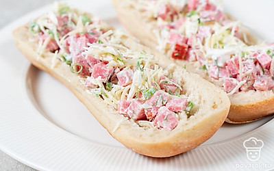 Багет разрежьте вдоль на две части. Аккуратно уберите мякиш. Нафаршируйте хлеб начинкой и отправьте в микроволновую печь на 3 минуты, чтобы сыр расплавился.