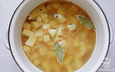 Поставьте на газ кастрюлю с водой, посолите ее, добавьте перец и лавровый лист. Нарежьте картофель кубиком среднего размера и переложите его вместе с отварной фасолью в кастрюлю с водой.