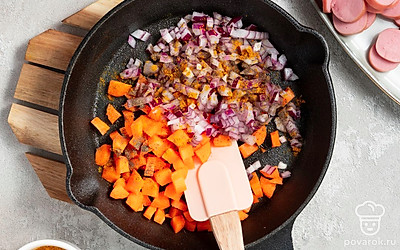 Начните готовить суп. В кастрюлю налейте воду и поставьте на сильный огонь. Поставьте сковороду на средний огонь и добавьте масло. Выложите морковь и лук на сковороду и тушите 7-10 минут. Поперчите и добавьте карри к моркови и луку.