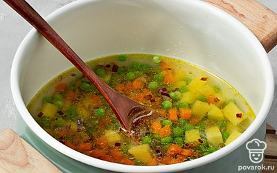Завершите приготовление. В закипевшую воду выложите картофель и варите 5 минут. Затем добавьте к нему горошек и варите еще 7 минут на среднем огне. Далее положите в суп зажарку из моркови и лука, перемешайте. Посолите суп по вкусу. Положите нарезанные сосиски и консервированную кукурузу, перемешайте и доведите до кипения. После того, как суп вскипит, снимите его с огня и посыпьте нарезанной зеленью.