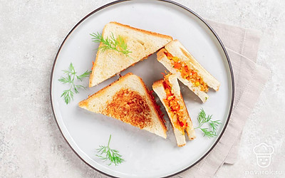 Готовые сэндвичи разрежьте по диагонали, чтобы получились треугольники. Украсьте свежей зеленью.