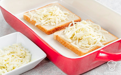 Моцареллу натрите на терке. Выложите кусочки хлеба в форму. Сверху посыпьте половиной сыра. 