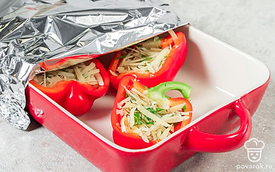 Разогрейте духовку до 160°C. При помощи ложки плотно нафаршируйте перцы сырной начинкой. После этого переложите заготовки в форму и накройте их фольгой. Уберите форму в духовку на 10 минут. Затем снимите фольгу и оставьте перцы запекаться еще 10 минут.