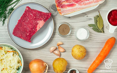 Говядину тщательно промойте и нарежьте кусочками. Морковь сполосните водой, очистите, нарежьте соломкой или брусочками. Очистите лук и чеснок от шелухи. Лук и бекон нарежьте кубиками среднего размера. Картофель очистите и нарежьте произвольными кусочками. Укроп помойте и вместе с чесноком разомните в ступке. Подготовьте кастрюлю и сковороду, а духовку разогрейте заранее до 150 градусов. Совет: для измельчения моркови можно использовать терку для корейских салатов.