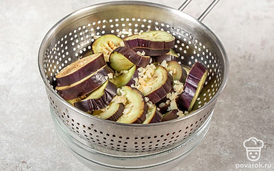 Процедите отвар через сито в отдельную емкость. Дождитесь, пока вся вода стечет. Измельчите чеснок и смешайте с баклажанами. Оставьте мариноваться на 30 минут.