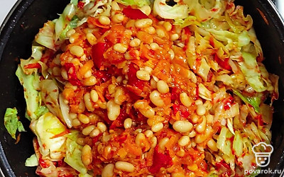 После того, как Вы поджарите лук и морковь, добавьте в сковороду фасоль, томатную пасту и капусту. Накройте крышкой и протушите 10-15 минут.