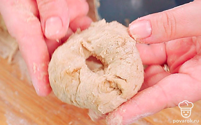 Разделите тесто на равные части, стараясь не подсыпать еще муки. Скатайте тесто в шарики, слегка их приплюсните и сделайте отверстие в центре каждого шарика.