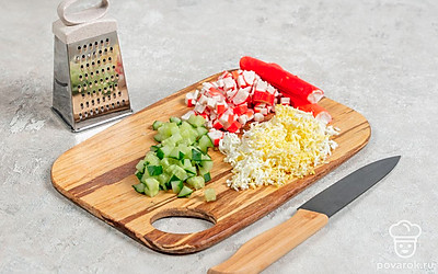 Отварите яйцо вкрутую. Обдайте холодной водой, снимите скорлупу. Натрите яйцо на мелкой терке. Нарежьте огурец и крабовые палочки небольшими кубиками.