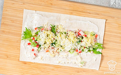 Раскатайте лаваш на столе. Смешайте майонез, пропущенный через пресс чеснок и щепотку соли. Нанесите смесь на лаваш, оставляя сверху и снизу свободные края по 1 см. Разложите ровным слоем салат. Выложите сверху крабовые палочки, а затем огурцы. Посыпьте тертым яйцом.