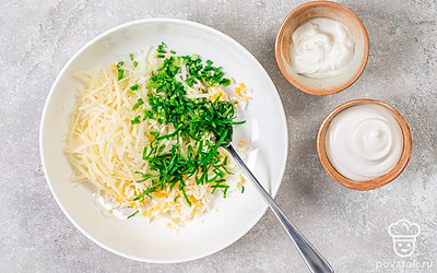 Натрите яйца и сыр на средней или мелкой терке. Переложите ингредиенты в небольшую миску. Измельчите лук и петрушку, добавьте к сыру и яйцам. Заправьте начинку сметаной и майонезом, посыпьте специями по вкусу и тщательно перемешайте.