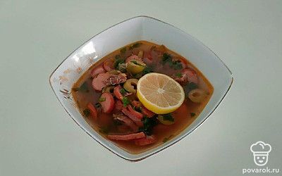 Солянку в тарелках подайте со сметаной. Добавьте пару кружочки лимона и рубленую зелень.