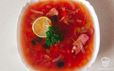 Солянку налейте в тарелки. Положите ложку сметаны. Отправьте в солянку кружочки лимона, нарезанные маслины.