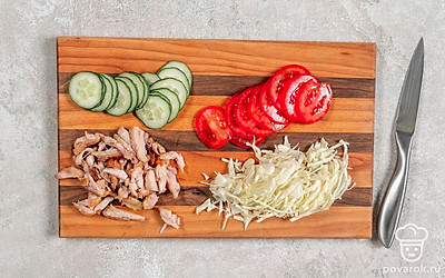 Пока курица запекается, нашинкуйте капусту и немного помните руками, чтобы она дала сок. Нарежьте огурцы и помидоры тонкими слайсами. Сделайте соус, смешав кетчуп с майонезом. Достаньте курицу из духовки, дайте ей немного остыть, очистите от кожи и костей, нарежьте мясо мелкой соломкой.