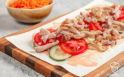 Разложите лаваш на столе. Смажьте соусом четверть лаваша, немного отступив от края. Выложите капусту, затем слой огурцов и слой помидоров. Поверх положите курицу и корейскую морковь. Подогните края по боками, чтобы начинка не вываливалась, и сверните в рулет.