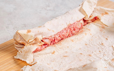 Разложите лаваш на рабочей поверхности. Равномерно распределите начинку на поверхности лаваша, оставляя небольшой отступ по краям для заворачивания. 