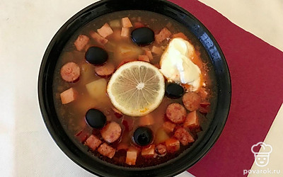 Подайте суп в одной большой глубокой посуде или в порционных тарелках. Посыпьте суп мелко нарезанной зеленью и небольшим количеством маслин без косточек. В соусницу вылейте сметану и также поставьте на стол со свежими ломтиками хлеба. Нарежьте дольку лимона и украсьте ею суп.