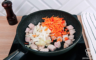 К мясу добавьте лук и морковь. Обжарьте все вместе.