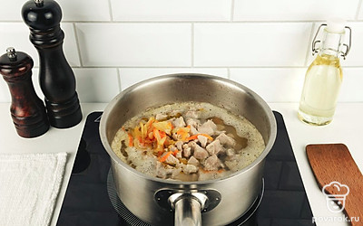 Добавьте в суп зажарку, нарезанную свинину, посолите и поперчите по вкусу. Перемешайте и варите гороховый суп еще 7-10 минут.