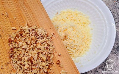 Натрите желтки и остатки белков. Смешайте их с натертым сыром, орехами. Выдавите чеснок. Все перемешайте.